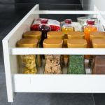 Modern kitchen countertop with food ingredients. Top view of drawers with spices organized inside.