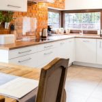 Spacious interior of a modern kitchen joined with a very stylish dining room with a large window overlooking the garden
