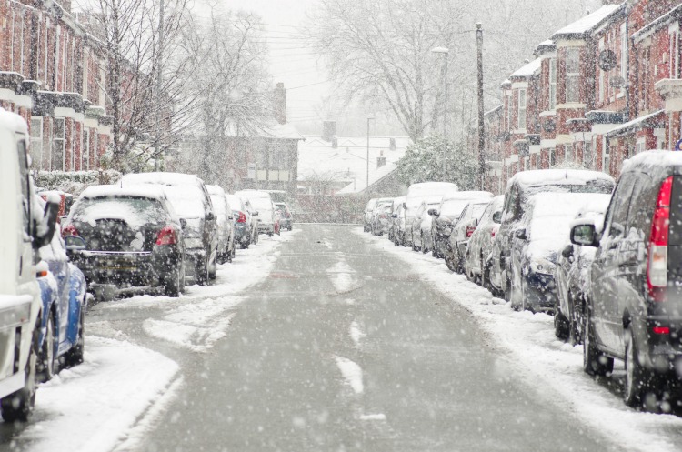 Manchester, England. Cars cover, houses of snow on street. The winter storm, causing flight delays and traffic problems.