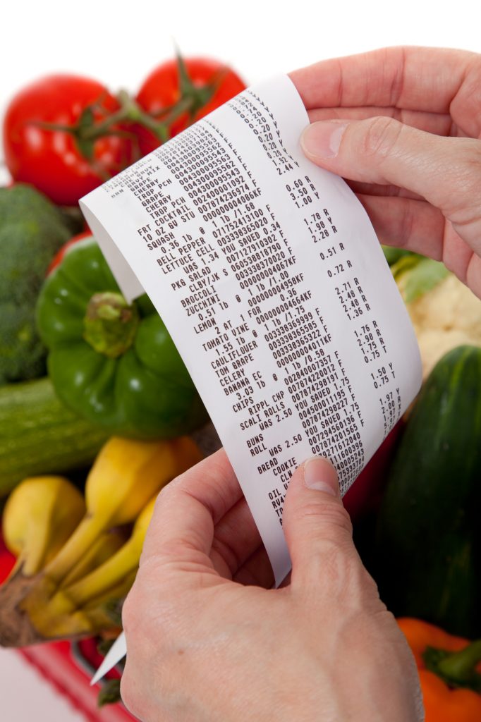 A grecery receipt over a bag of vegetables