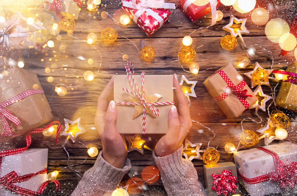 Top view of woman hands with gift box on wooden table.